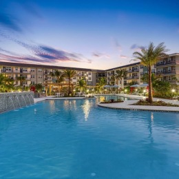 a pool in front of a building with palm trees